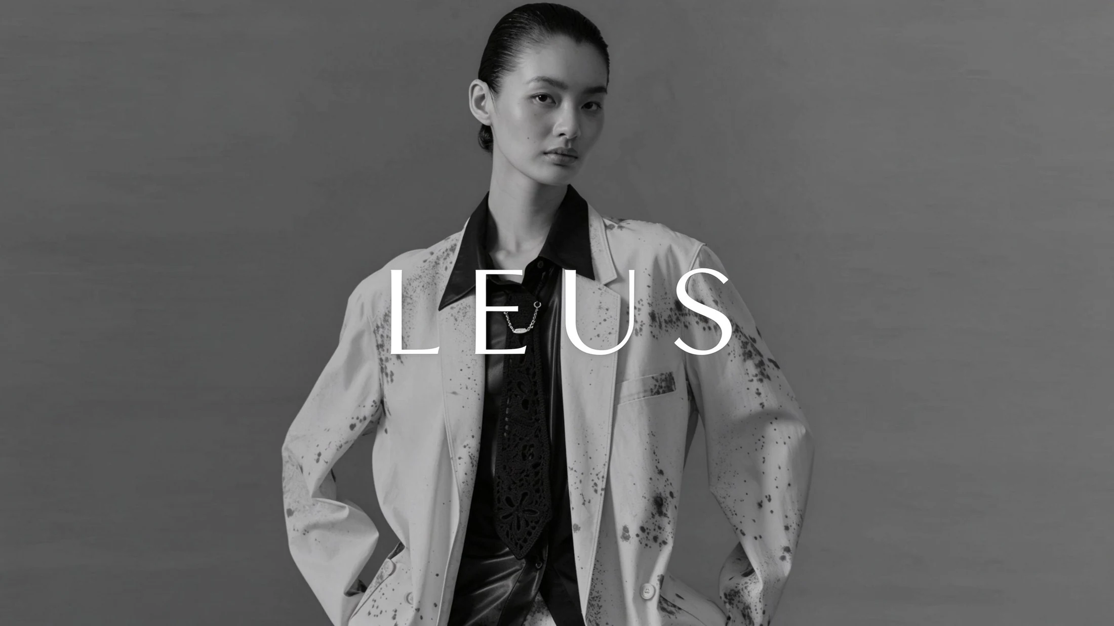 グレーの背景に立つLEUSのモデル